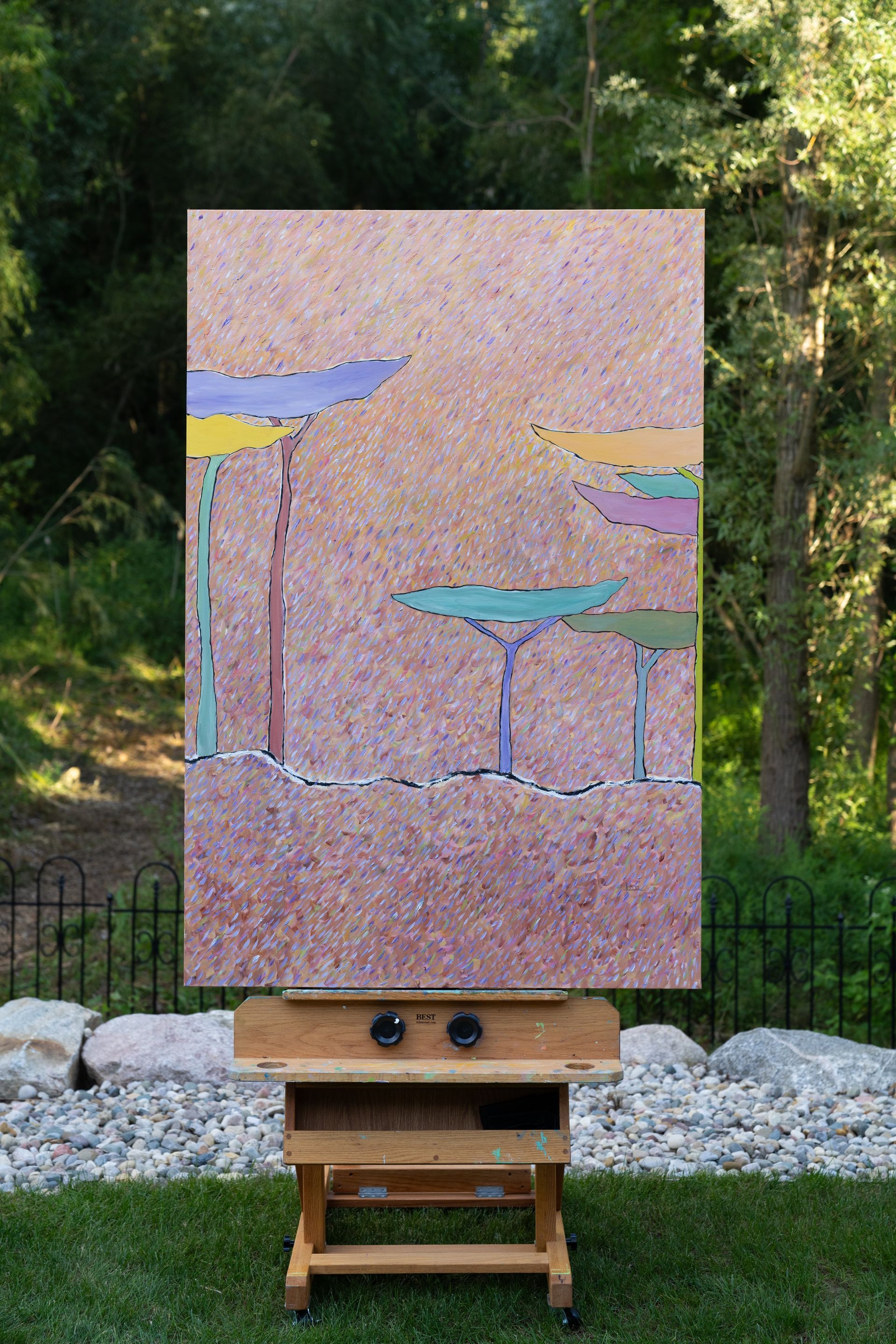 Painting on easel outdoors, dotted texture, stylized trees, muted colors: mauve, blue, green, yellow.