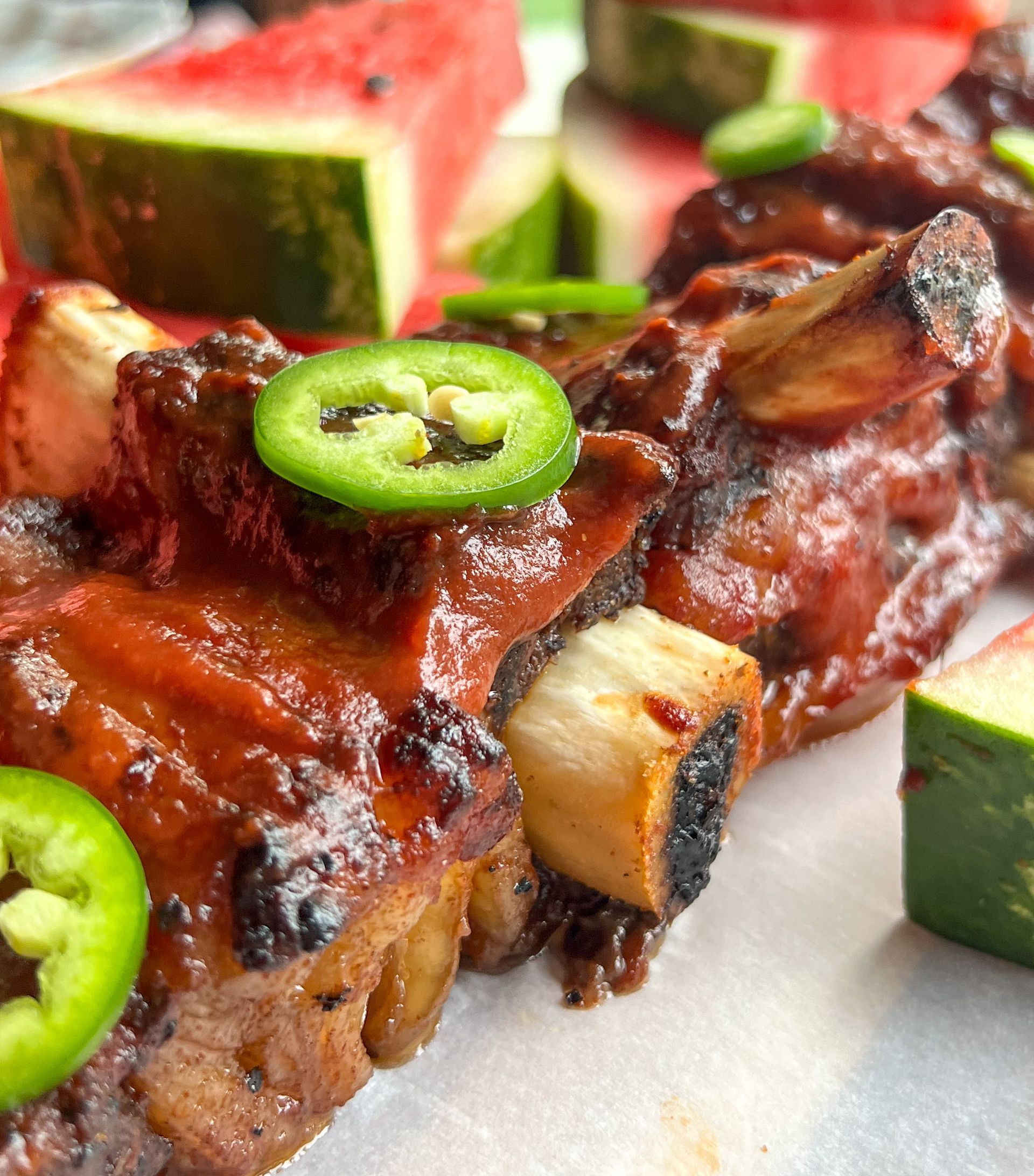 A close up of a piece of food with watermelon in the background