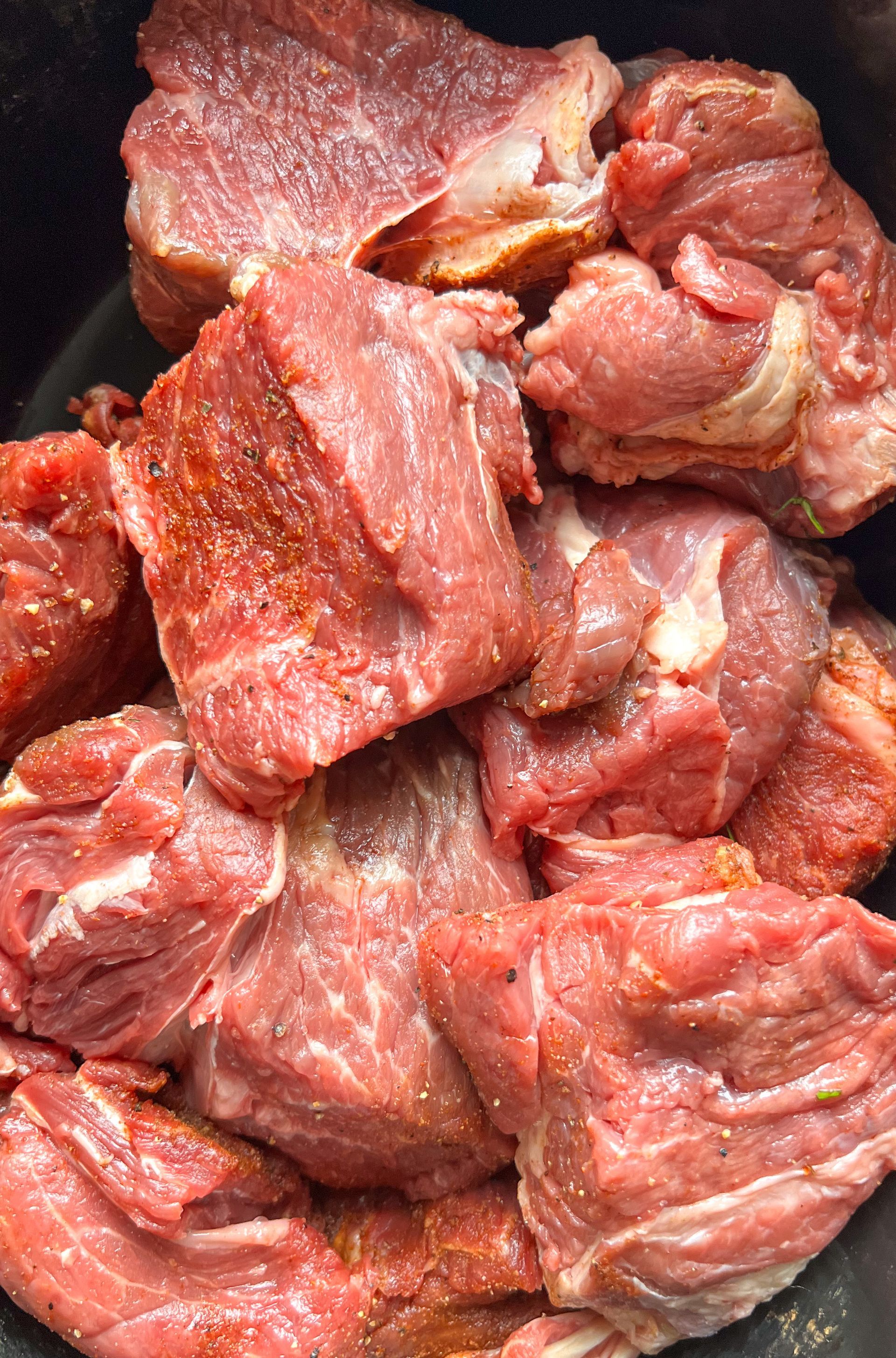 A close up of a pile of raw meat in a pan.