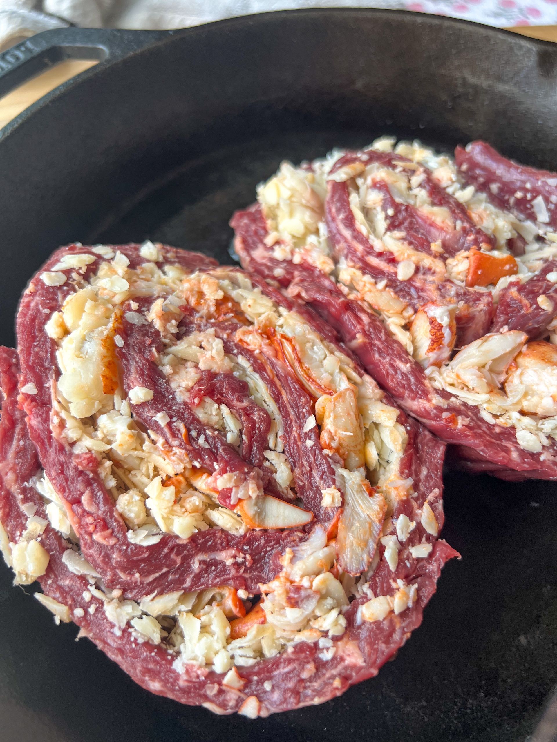 A skillet filled with meat and vegetables is sitting on a table.