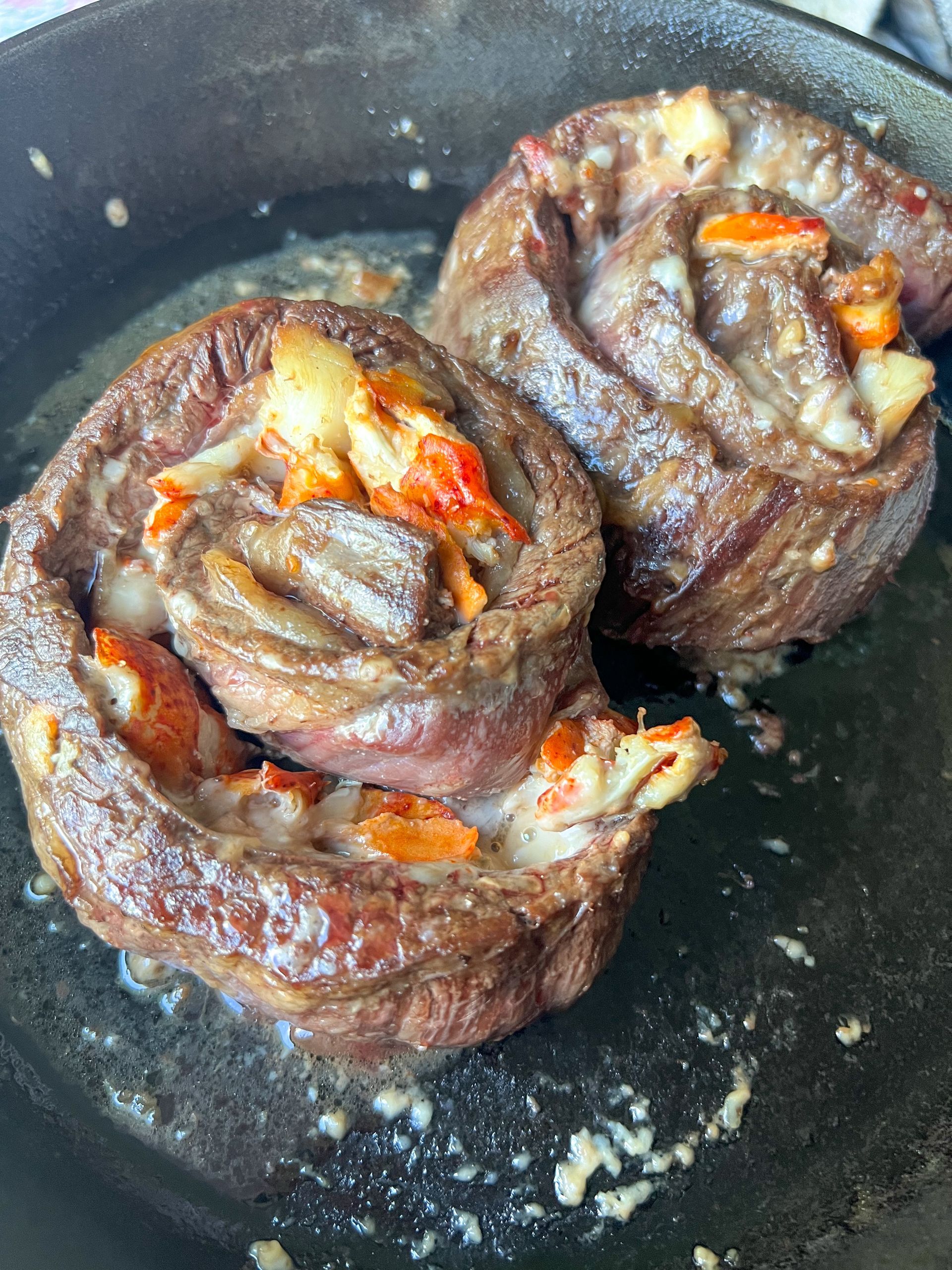 Two meat rolls are being cooked in a skillet.