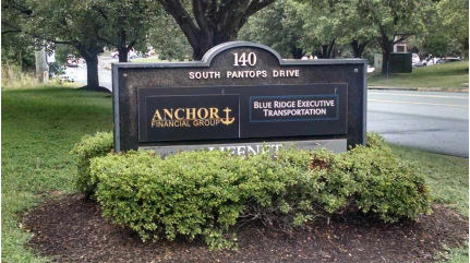 A sign for anchor financial group is surrounded by bushes
