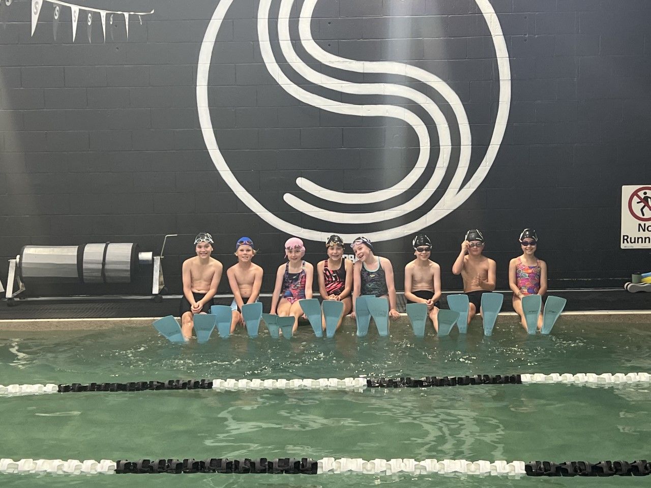 A group of children are posing for a picture in a swimming pool.
