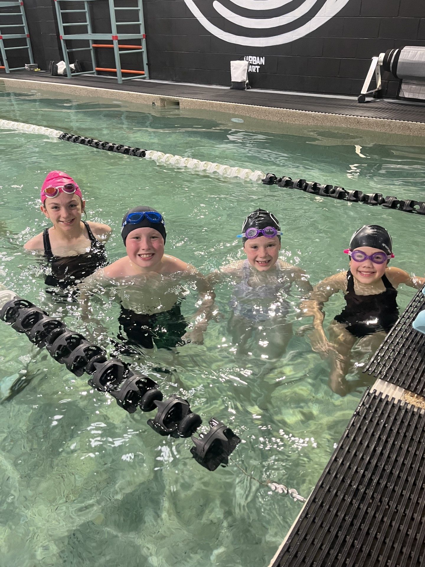 A group of young children are swimming in a swimming pool.