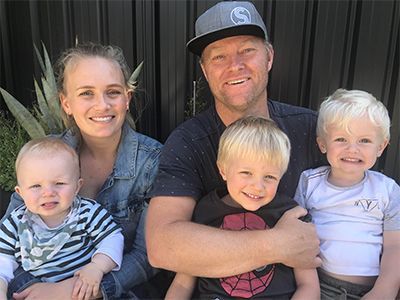 A family is posing for a picture together while sitting on a bench.