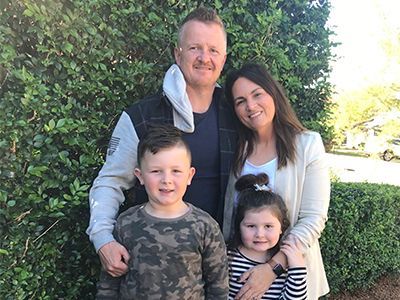 A family is posing for a picture in front of a bush.
