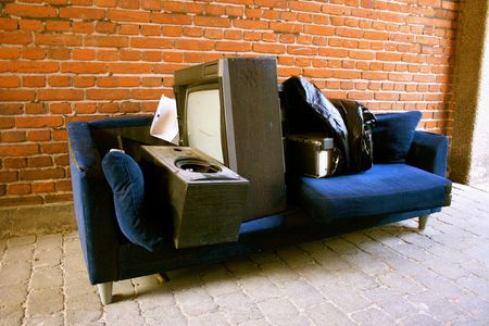 A blue couch with a tv on it in front of a brick wall