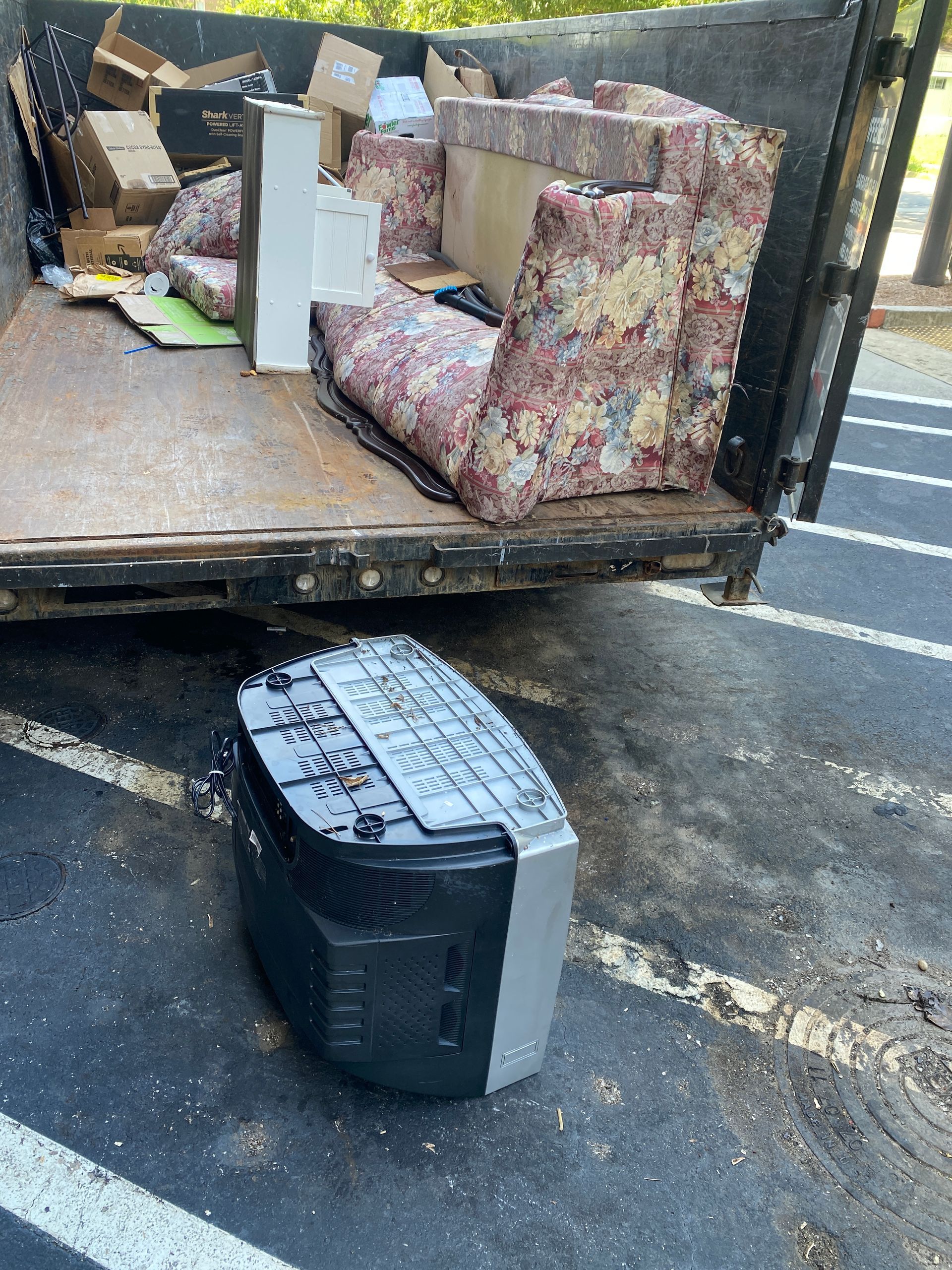 A television is sitting in front of a dumpster filled with furniture.