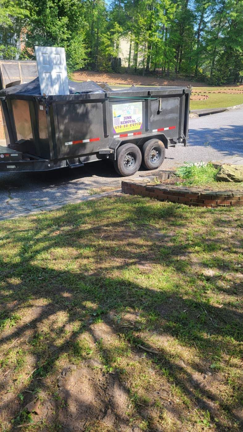 A dumpster trailer is parked in the grass in a driveway.