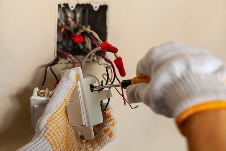 An electrician is replacing a wall switch.