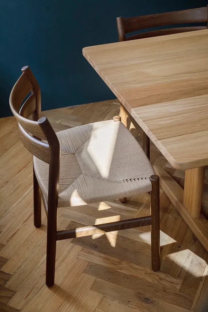 Neben einem Holztisch steht ein Holzstuhl.