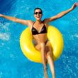 A woman in a bikini is floating on a yellow raft in a pool