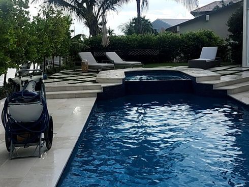 A large swimming pool with a vacuum cleaner sitting next to it.