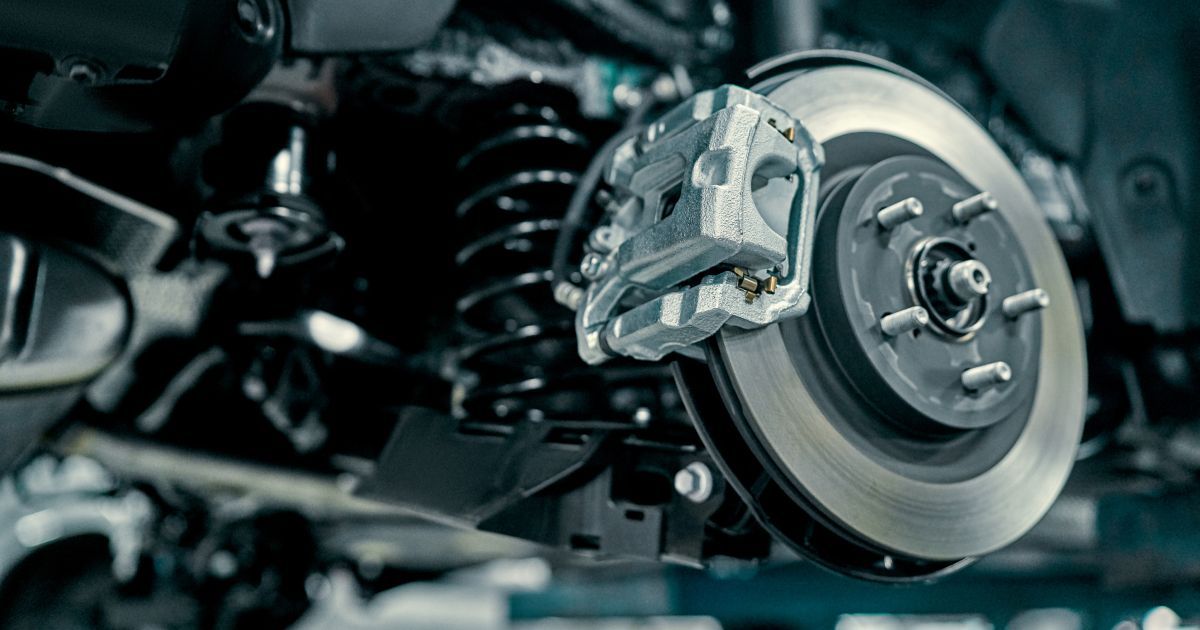 A close-up view of a car's rear suspension and disc brake system on a vehicle raised for maintenance.