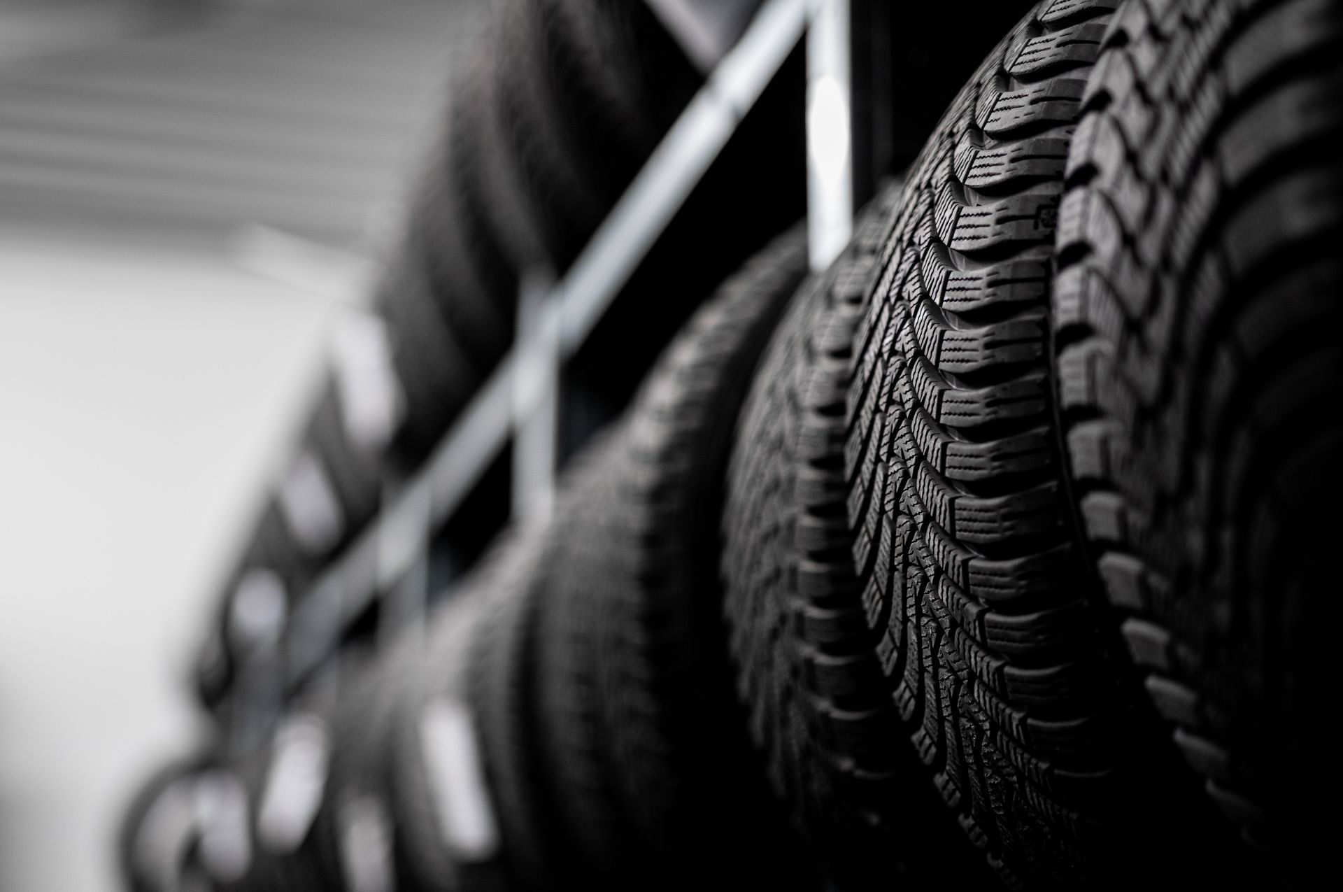A shallow depth of field view of several black car tires lined up on metal storage racks.