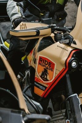 Bicycle with beige and red Ride Noms bags parked beside a cyclist in dark gear
