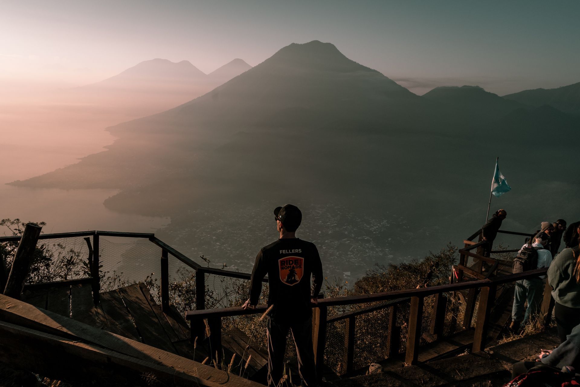 Person overlooking a misty mountain landscape at sunrise from a wooden viewpoint