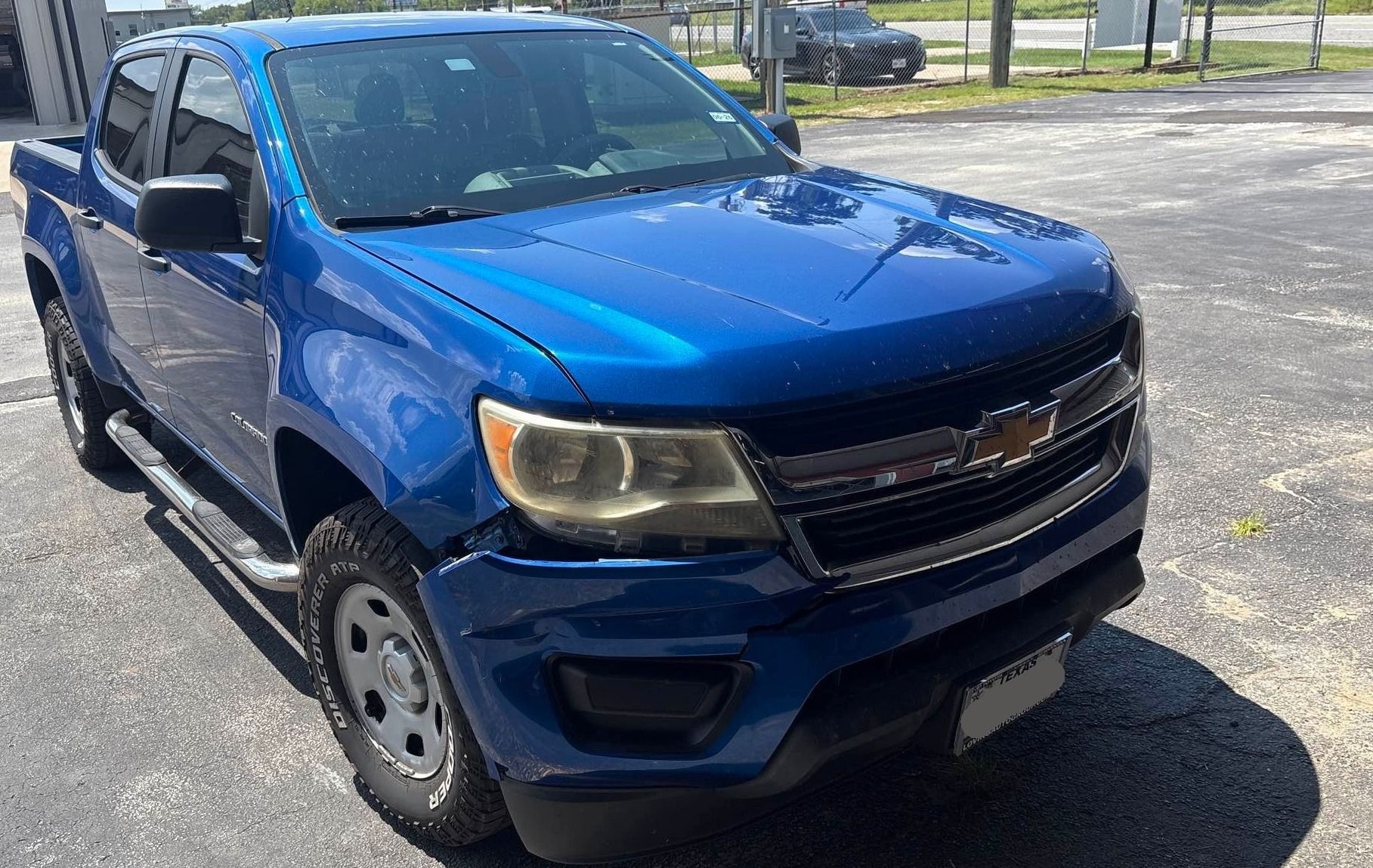 Blue Chevrolet Colorado pickup truck, damaged front, parked outdoors.