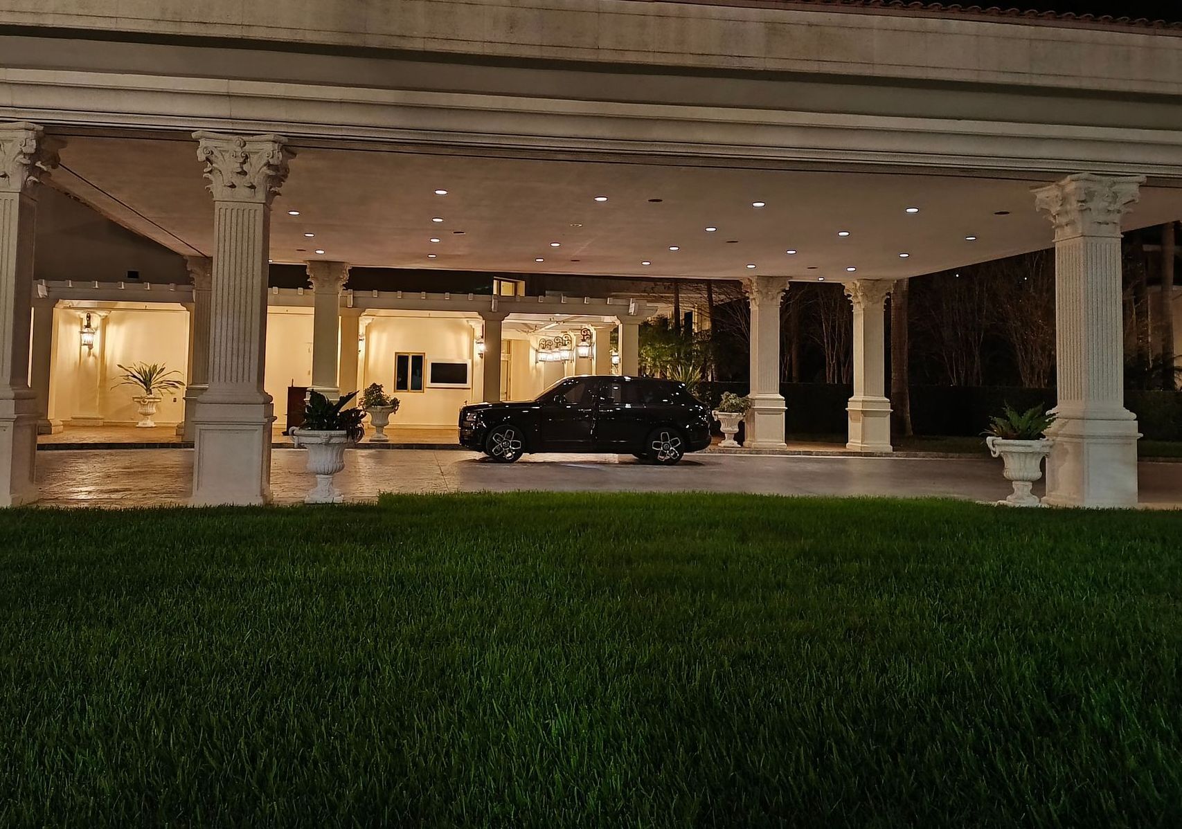 A black car is parked in front of a building at night