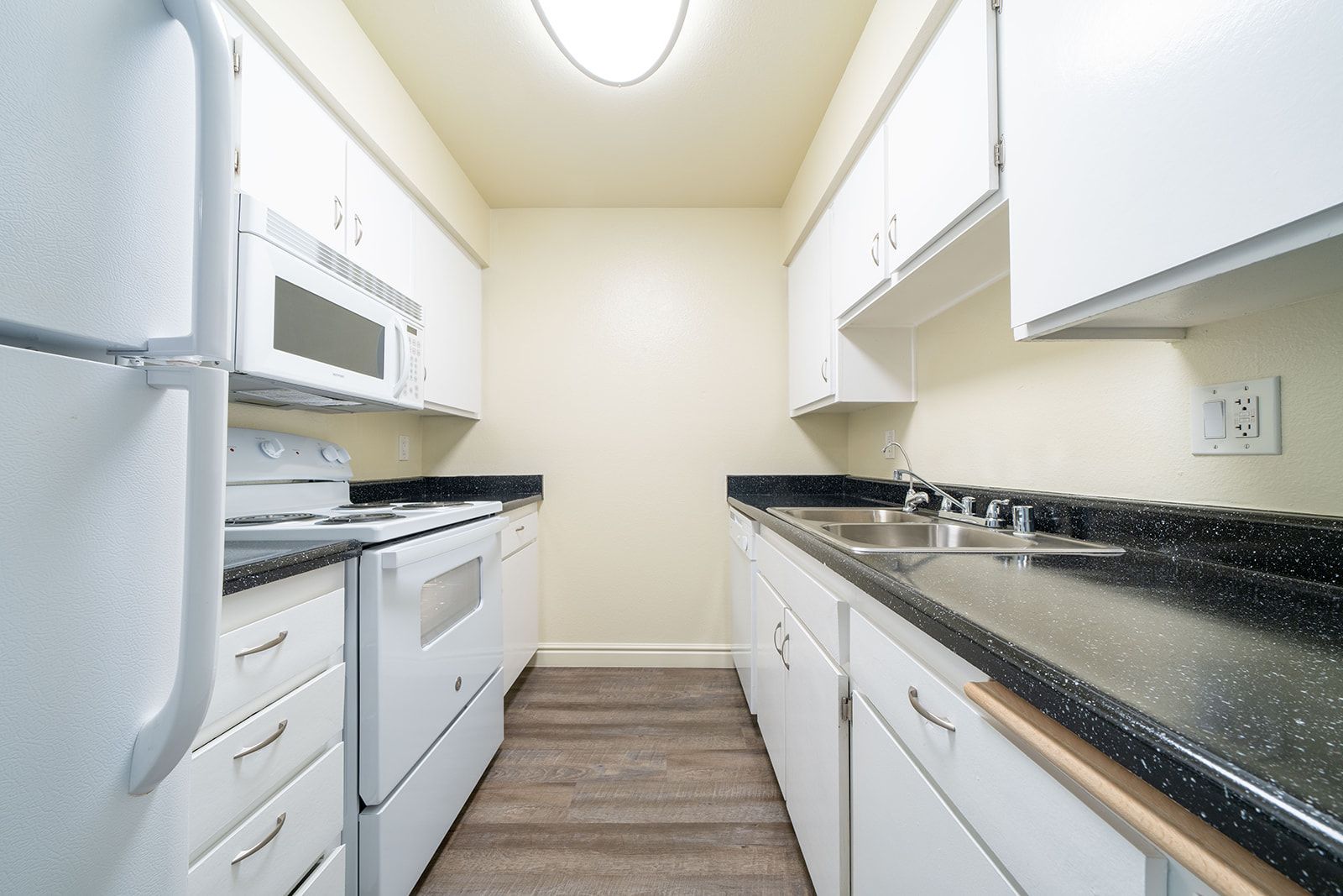 A kitchen with white cabinets and black counter tops