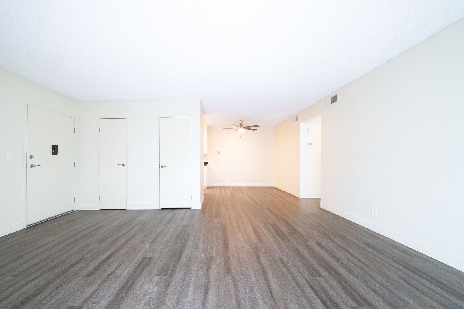 An empty living room with hardwood floors and white walls.