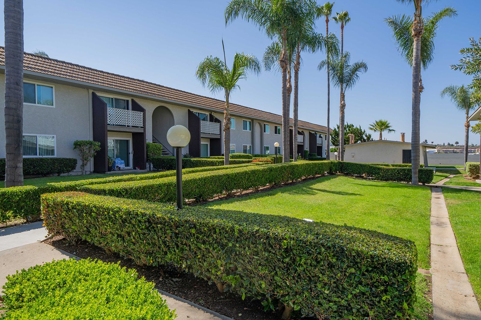 A large apartment building with a lush green lawn in front of it.