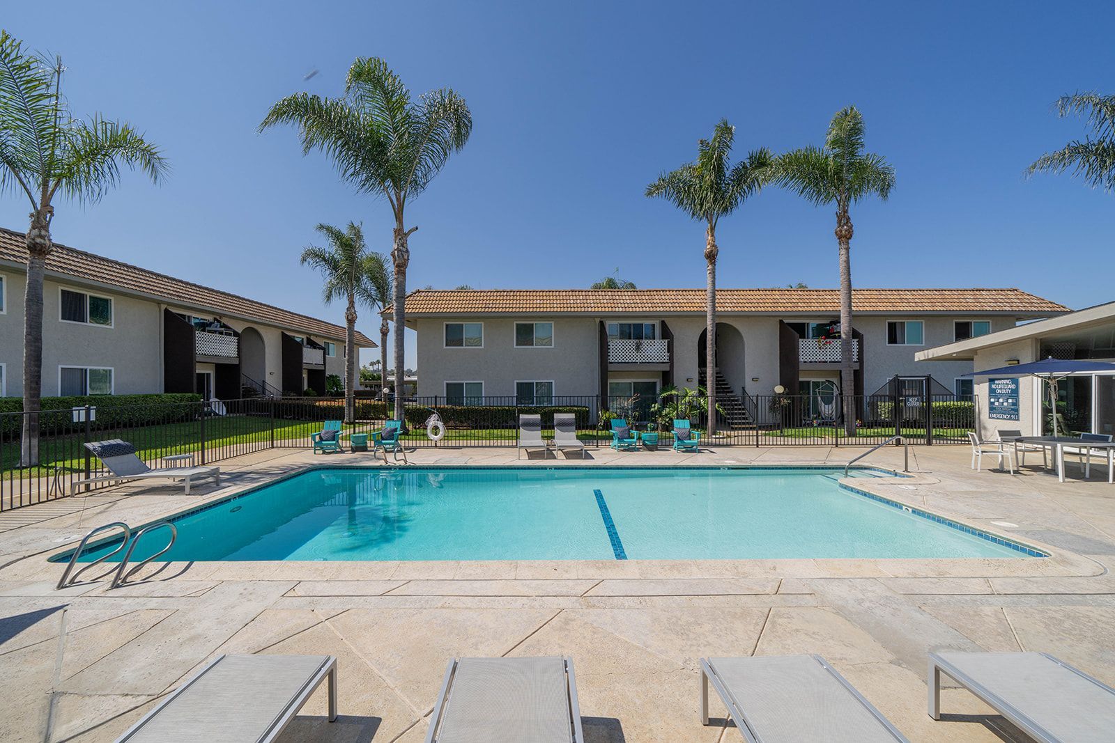 A large swimming pool in front of a building with palm trees