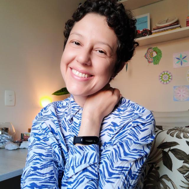 Uma mulher vestindo uma camisa azul e branca com estampa de zebra está sorrindo