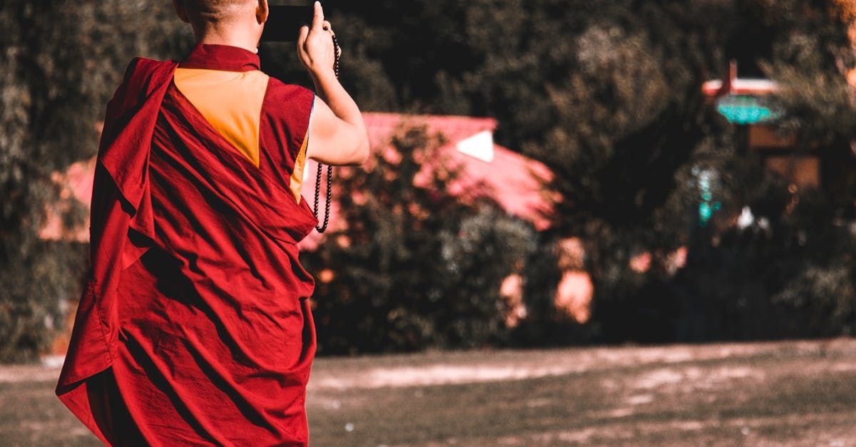 A monk in a red robe is walking down a street.