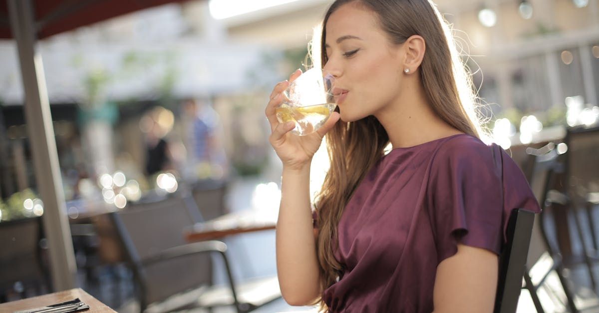 A woman is drinking a glass of wine while sitting at a table.