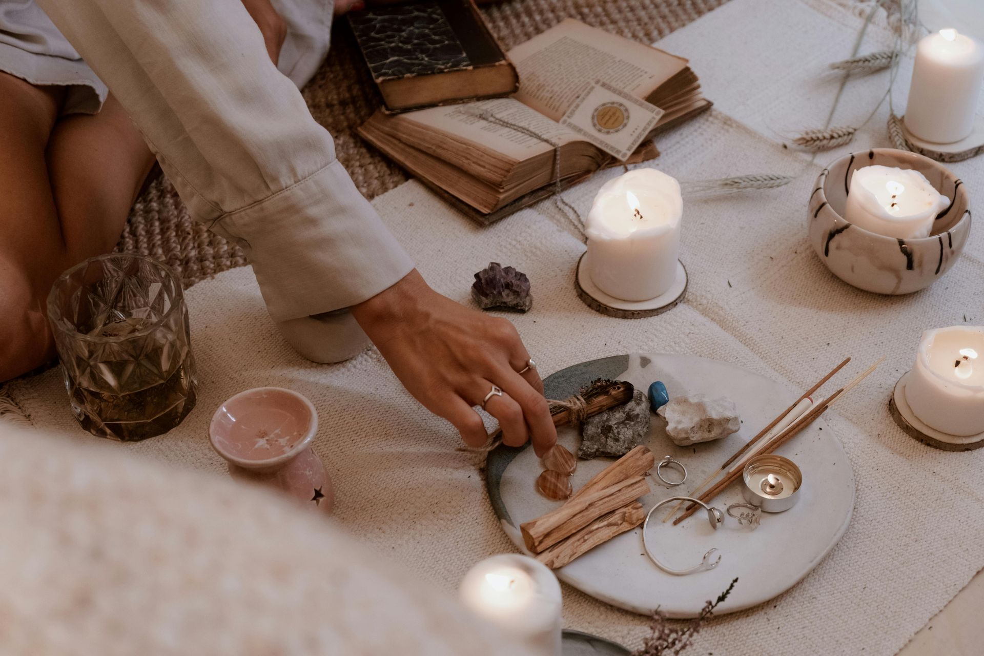 Espiritualidade e Religião A person is sitting on the floor surrounded by candles and crystals.