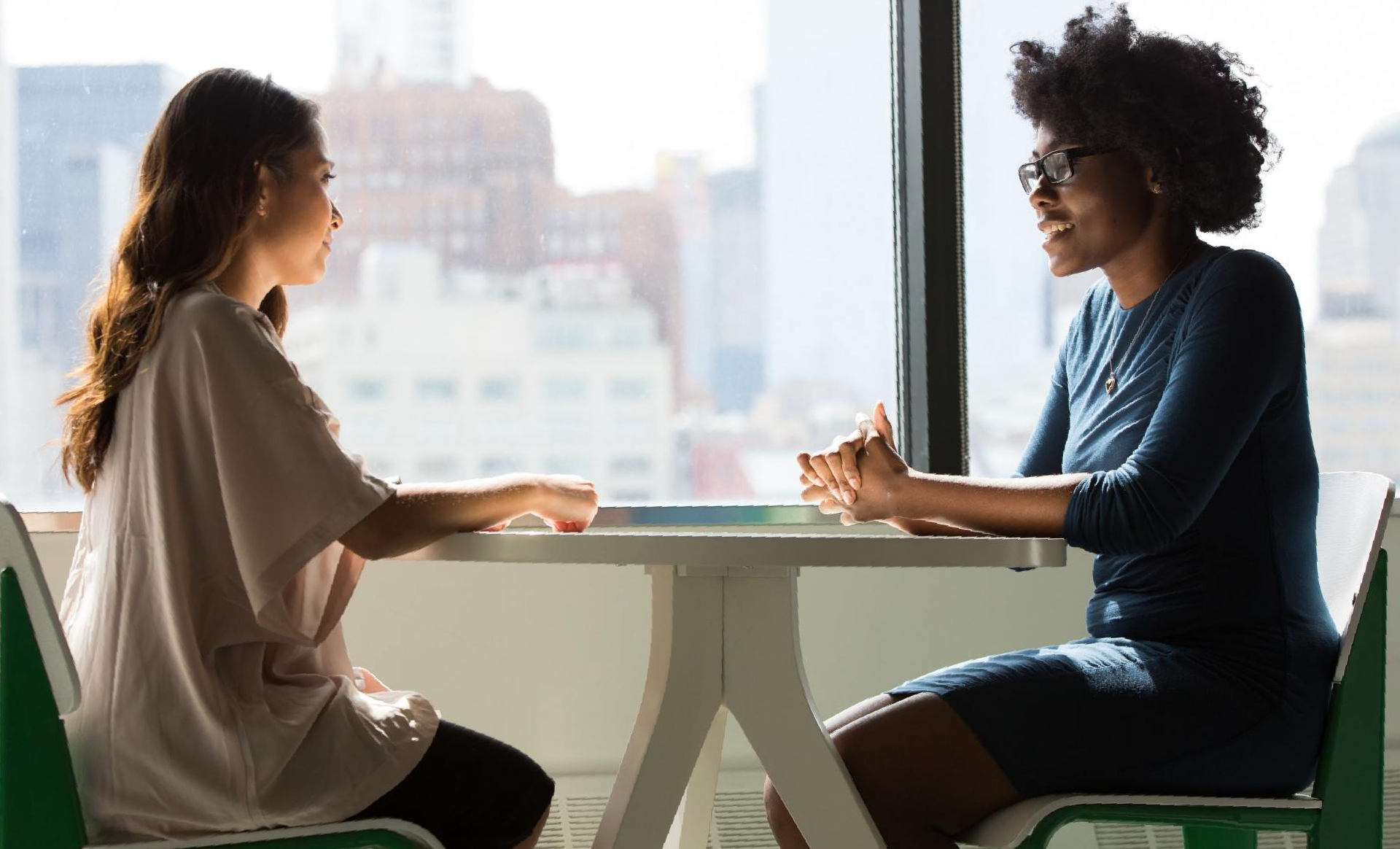 Duas mulheres estão sentadas à mesa conversando.