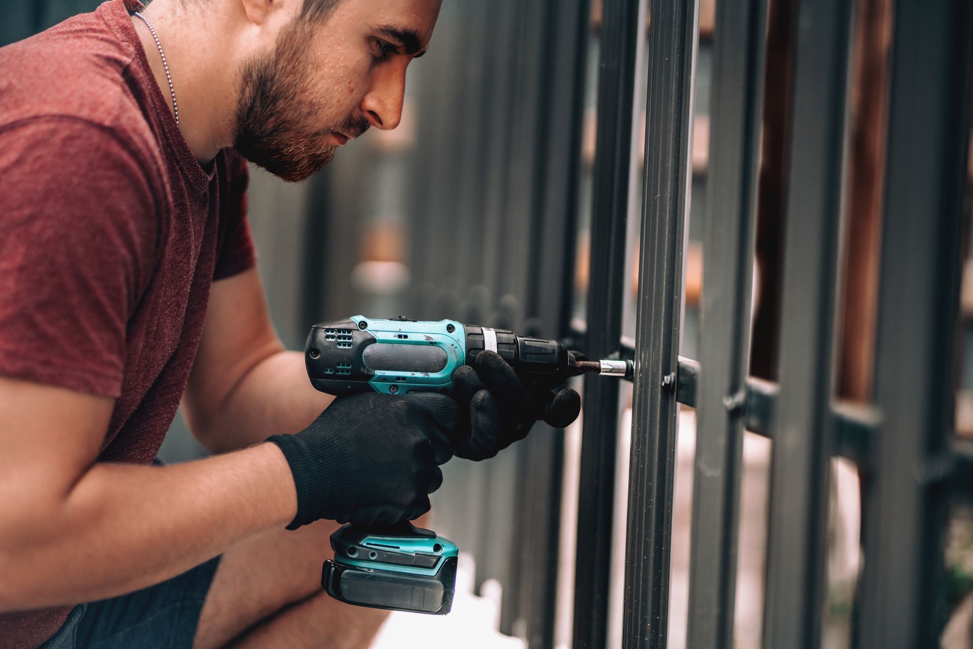 Worker drilling screws into a metal fence for a professional fence installation company.