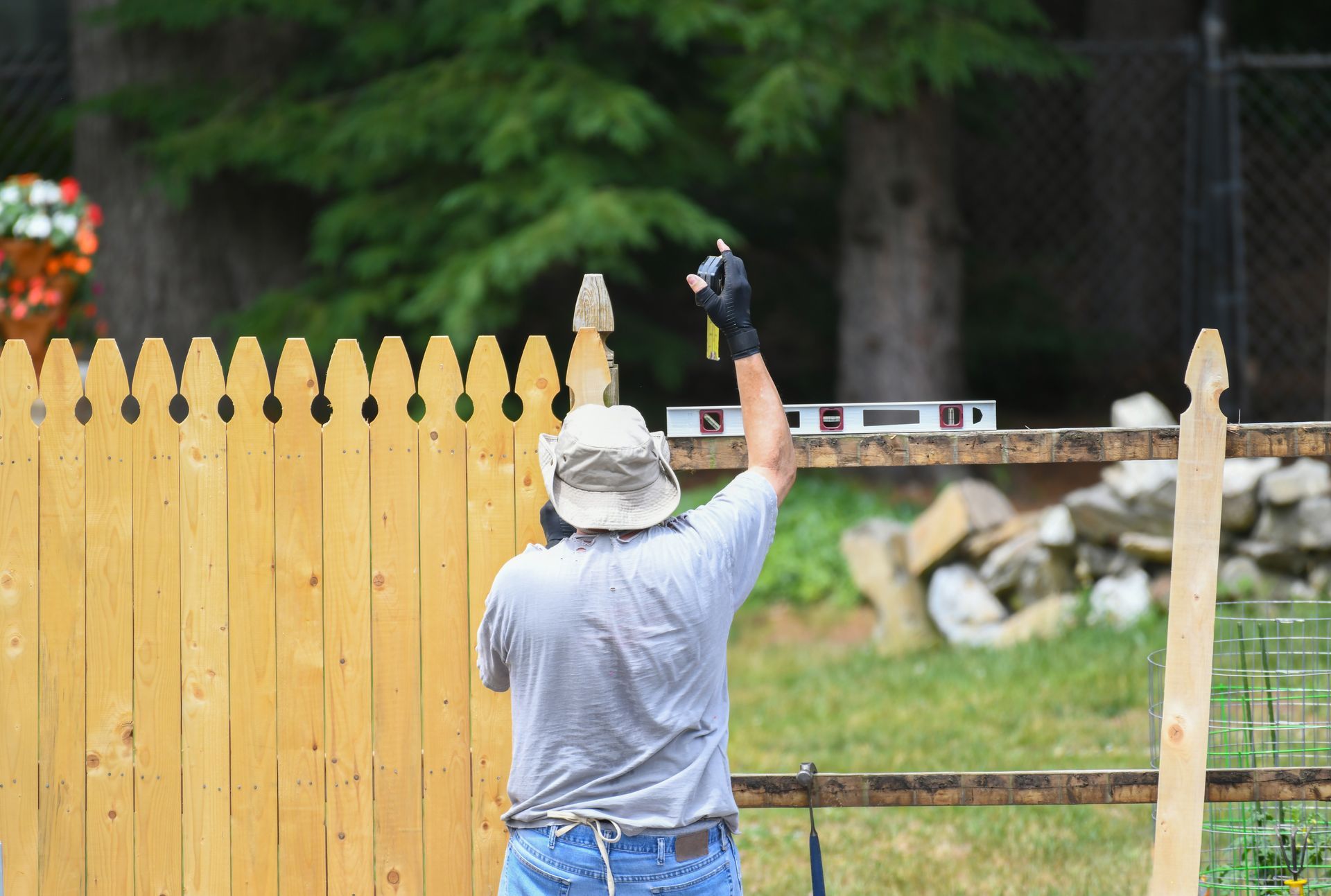 A male worker installing a wood fence in a residential yard.