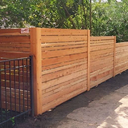 Wooden horizontal slat fence with a black metal gate, in an outdoor setting.