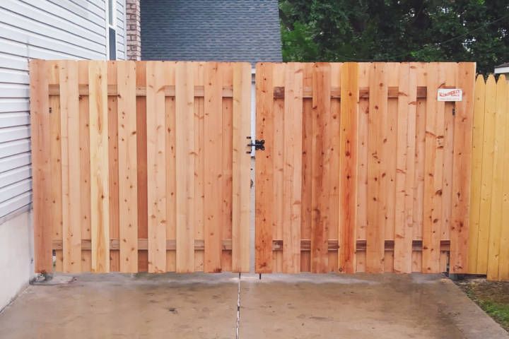 Wooden gate with vertical planks, on a concrete driveway.