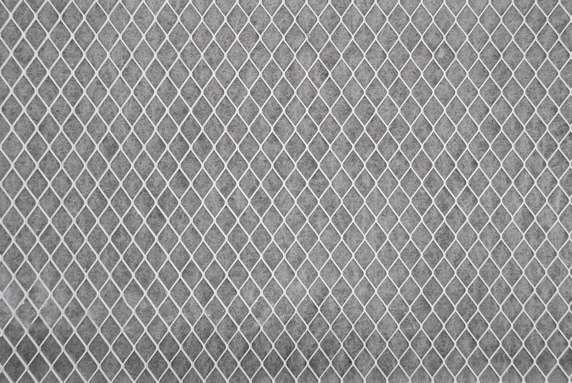 Diamond-patterned metal mesh against a gray textured background.