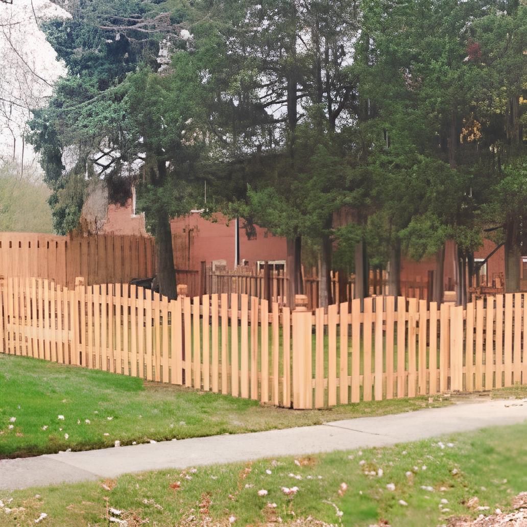 Wooden picket fence around a grassy yard, trees and a brick house in the background.