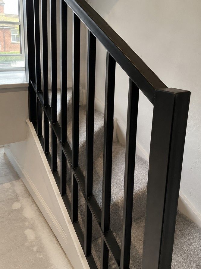 Bespoke mild steel vertical bar balustrade on a residential staircase, fabricated and installed by Nottingham Metalworks