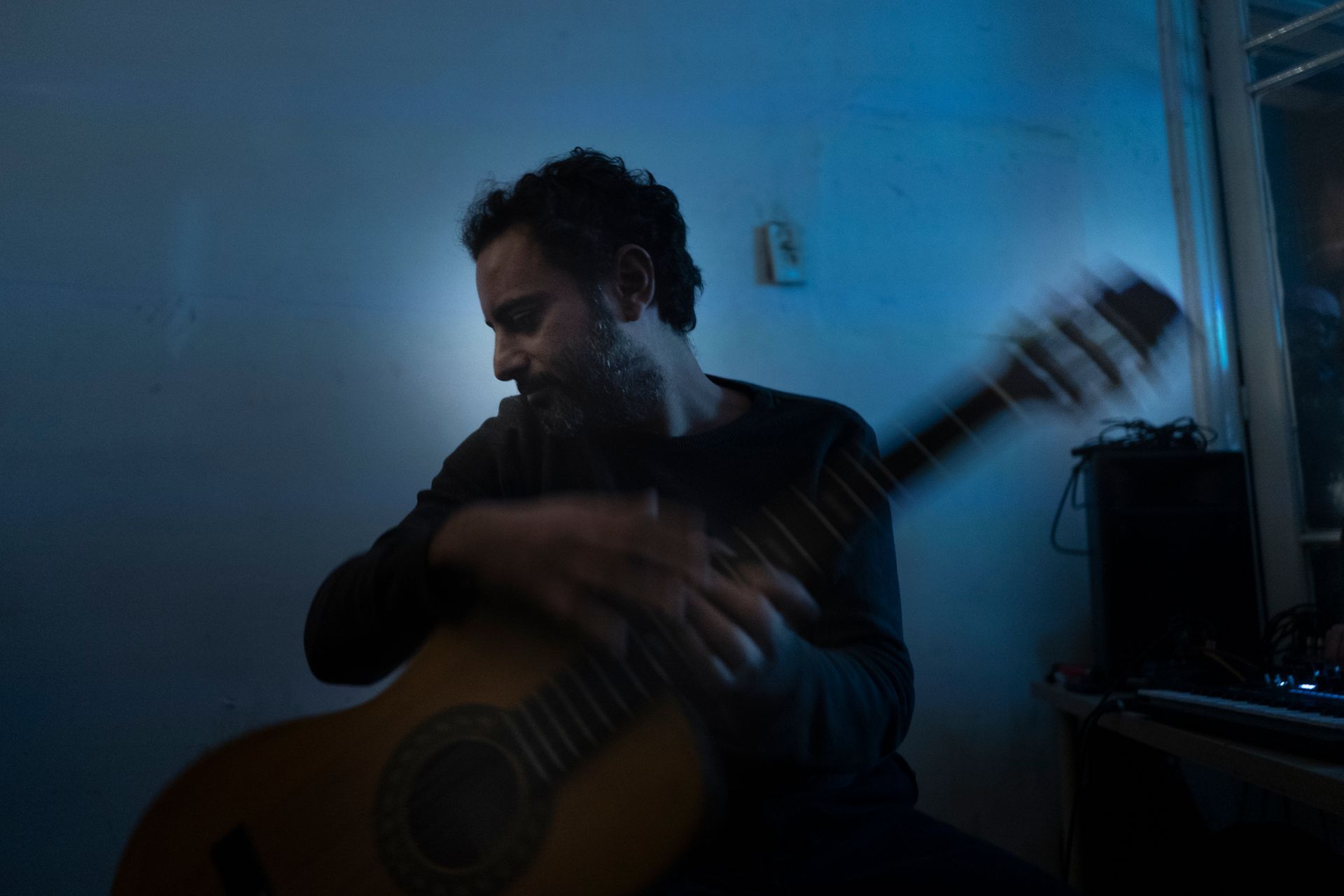 Maurice Louca is playing a guitar in a dark room. Photo by Aalam Wassef
