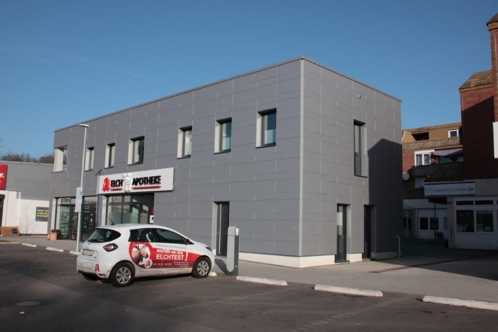 Ein weißes Auto steht vor einem Gebäude mit der Aufschrift „Kasse“