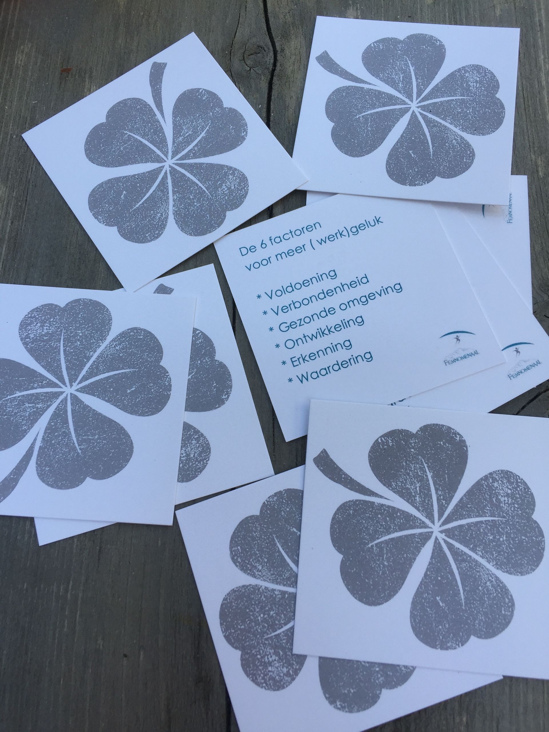 Witte kaarten met grijze klavertje vier-stempels, één met een handgeschreven lijst in turquoise inkt.