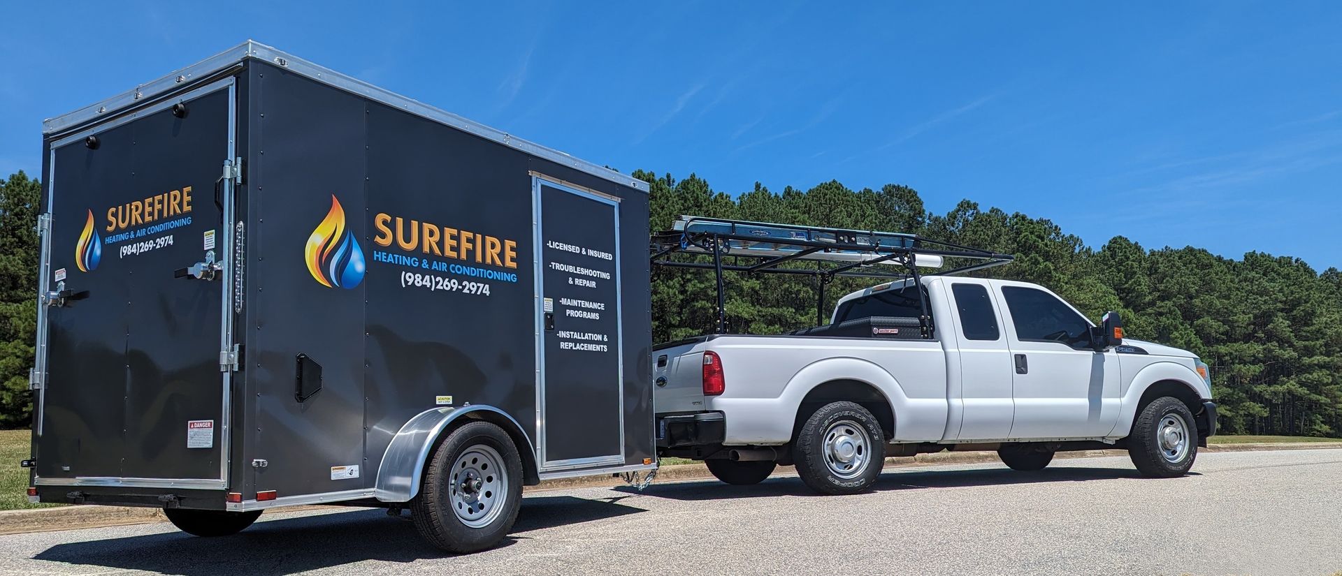 Surefire Heating & Air Conditioning work truck, with trailer that has the company logo