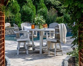 A patio with a table and chairs next to a pool. A patio with a table and chairs next to a pool.