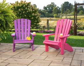 Two purple and pink adirondack chairs are sitting on a patio. Two purple and pink adirondack chairs are sitting on a patio.