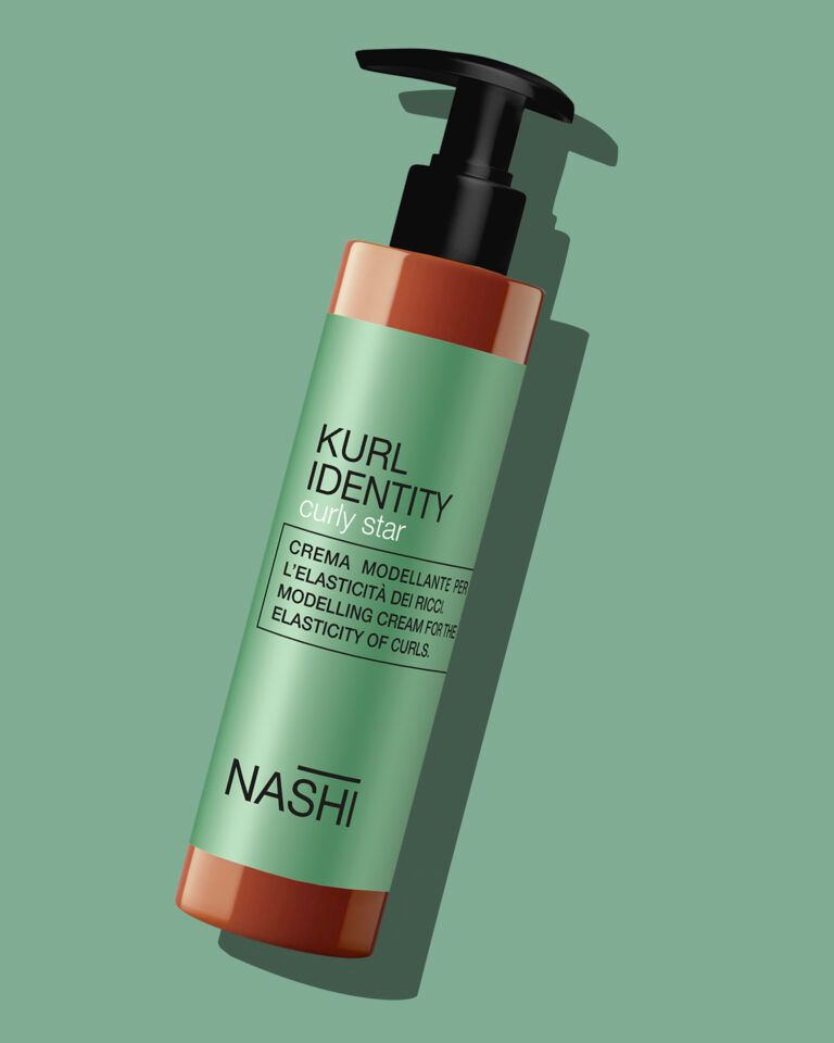 Una bottiglia di balsamo Nashi Curl Identity è appoggiata su una superficie verde.