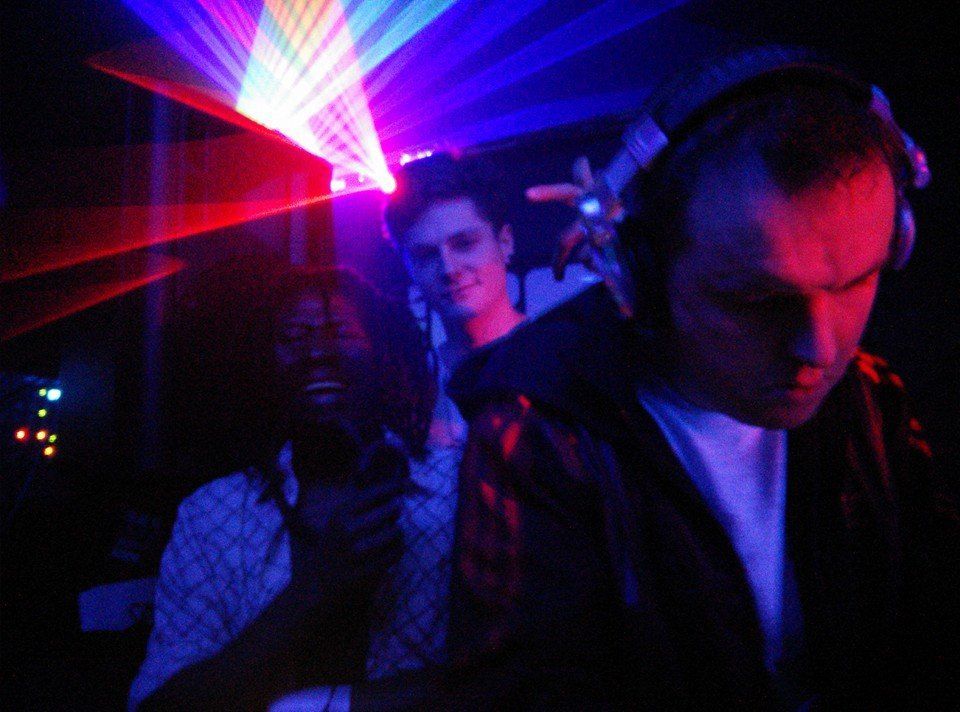 People dancing in a dark nightclub under vivid red, blue, and purple laser lights
