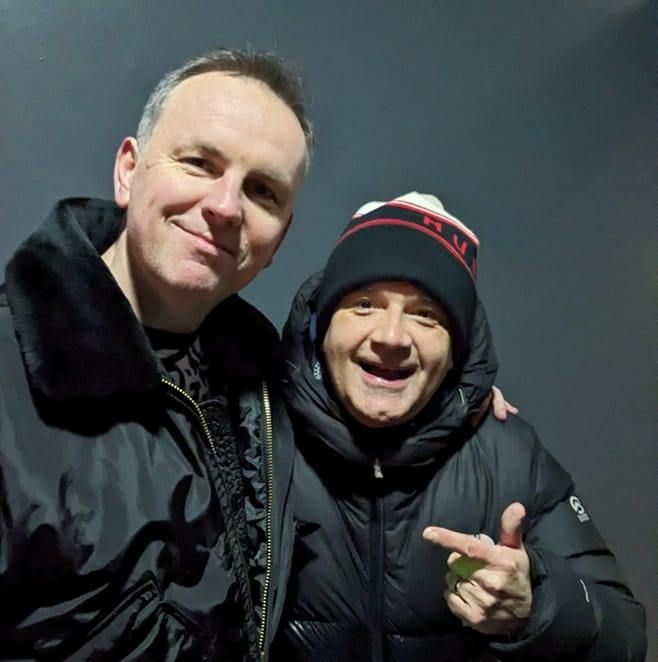 Two smiling people in black winter jackets posing together outdoors at night