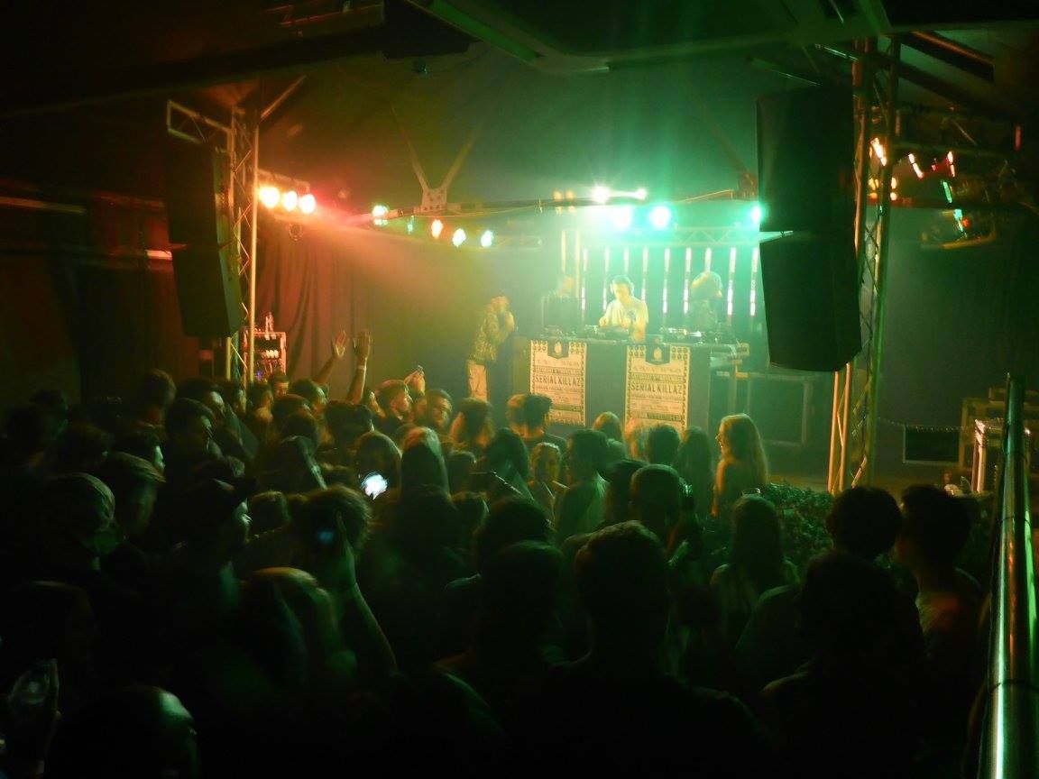 Crowded concert venue with colorful stage lights and a performer on stage