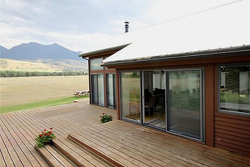 A house with a large deck and mountains in the background